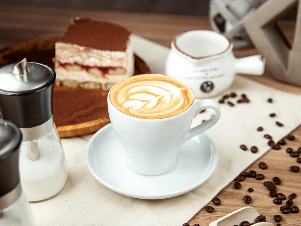 Cappuccino cu latte art și tiramisu pe masă
