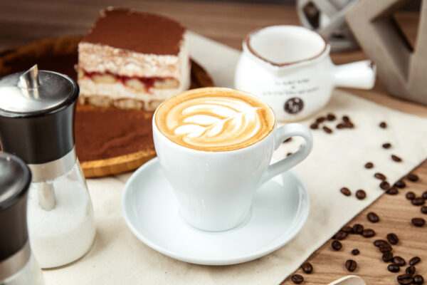 Cappuccino cu latte art și tiramisu pe masă