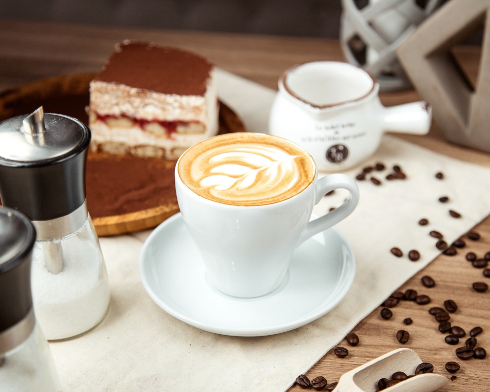 Cappuccino cu latte art și tiramisu pe masă
