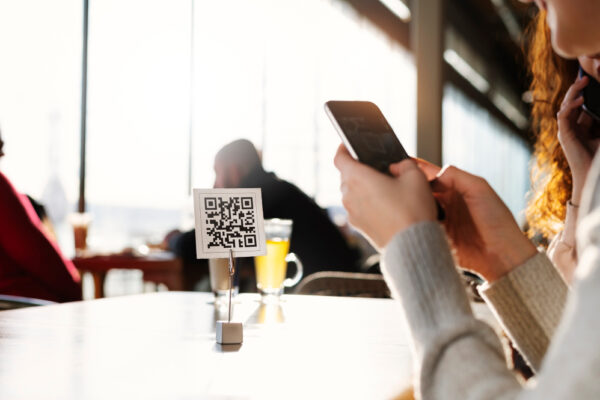 Femeie scanează cod QR într-o cafenea