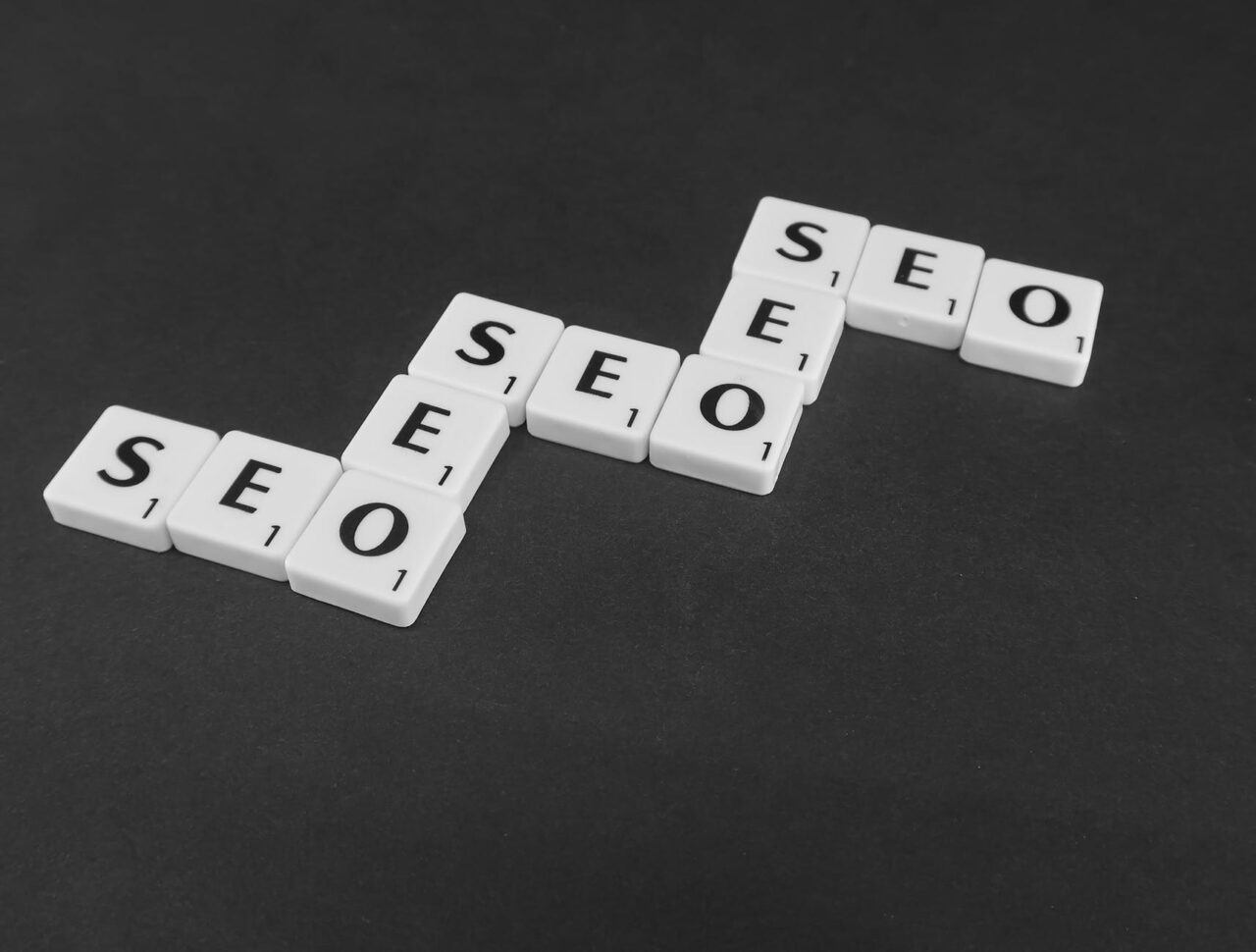 Piese Scrabble formând cuvântul SEO pe fundal închis
